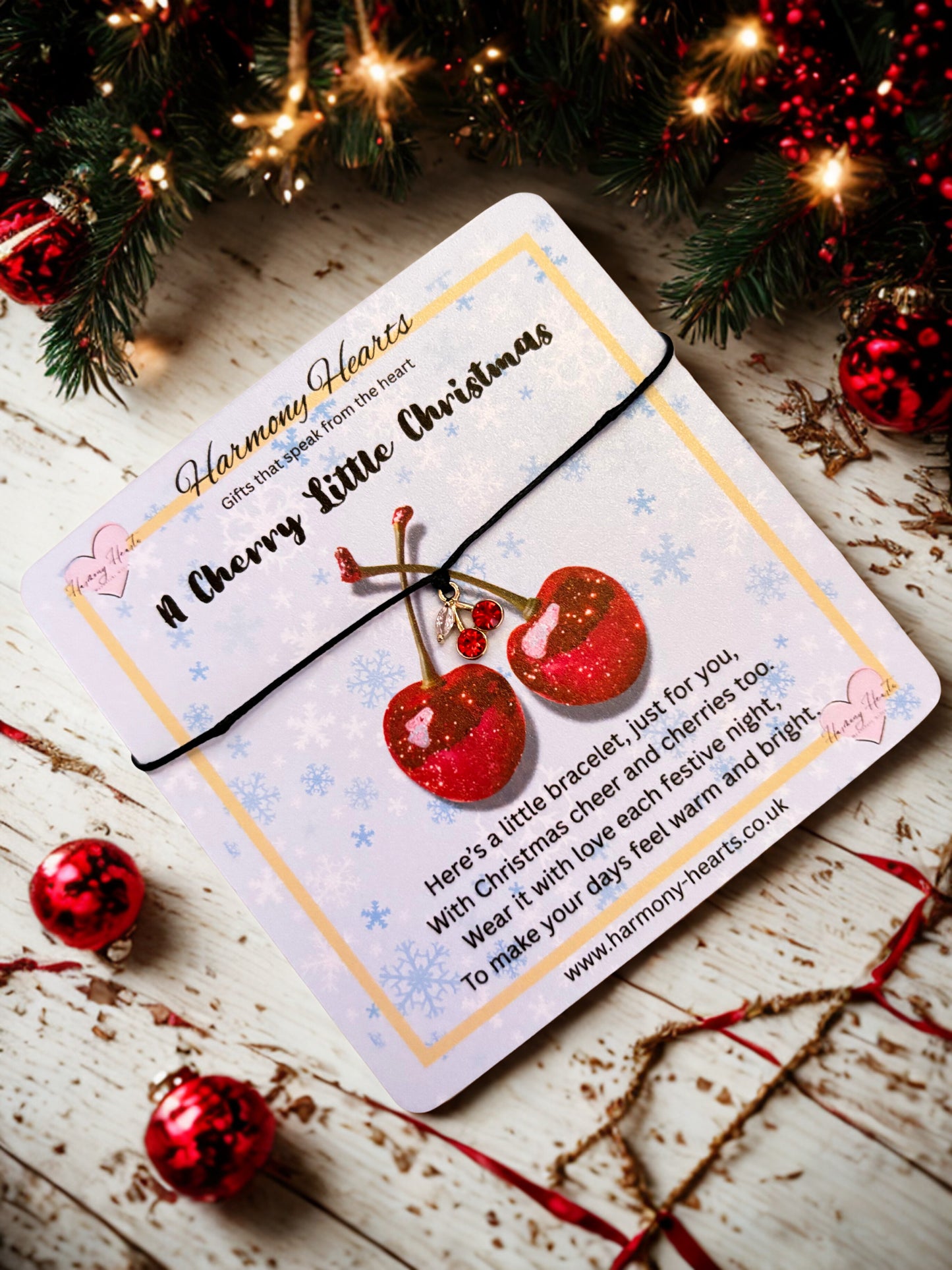 Christmas-themed card with red glittery cherries and festive decorations on a wooden surface.