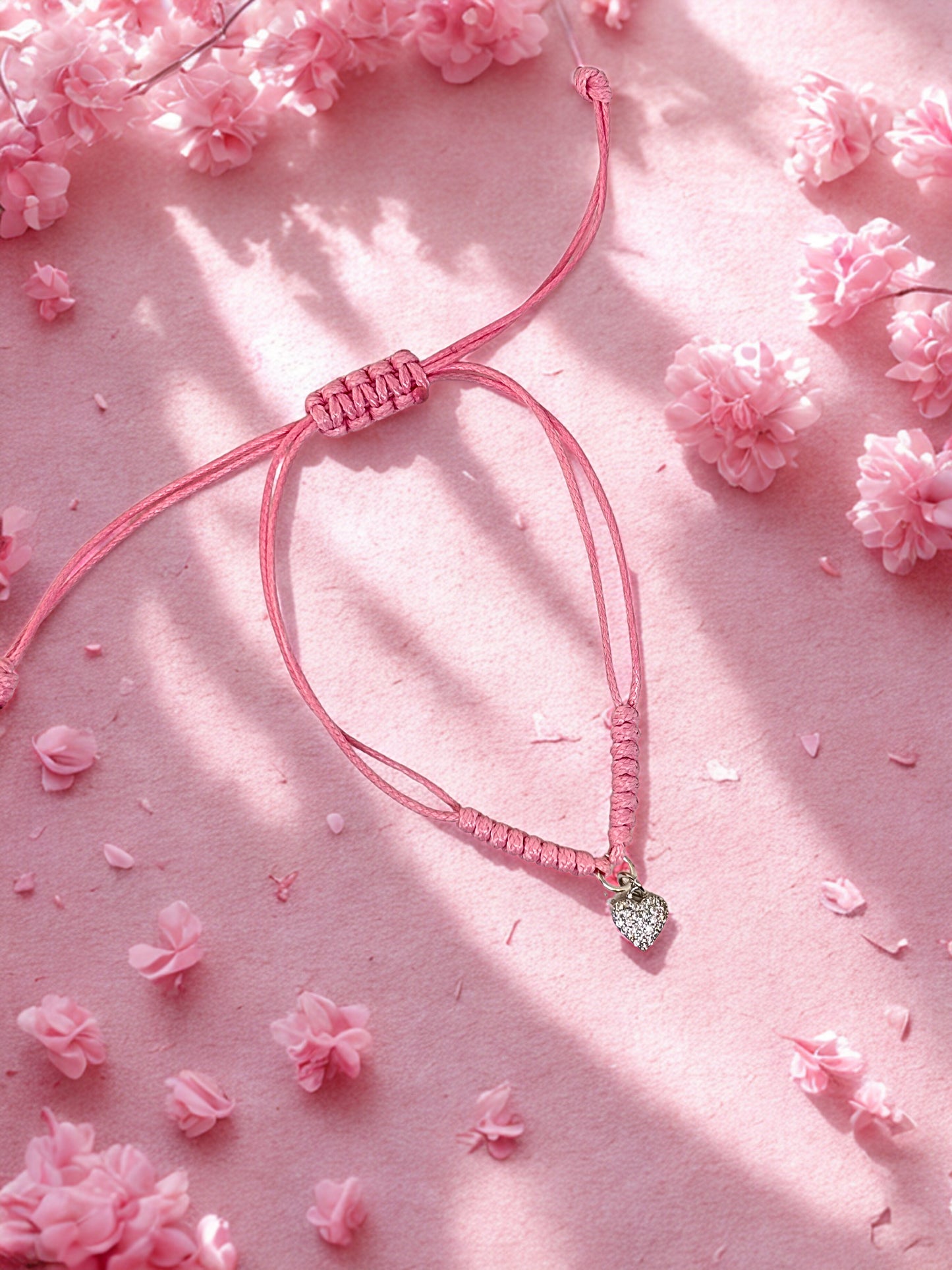 Pink bracelet with a heart charm on a pink floral background