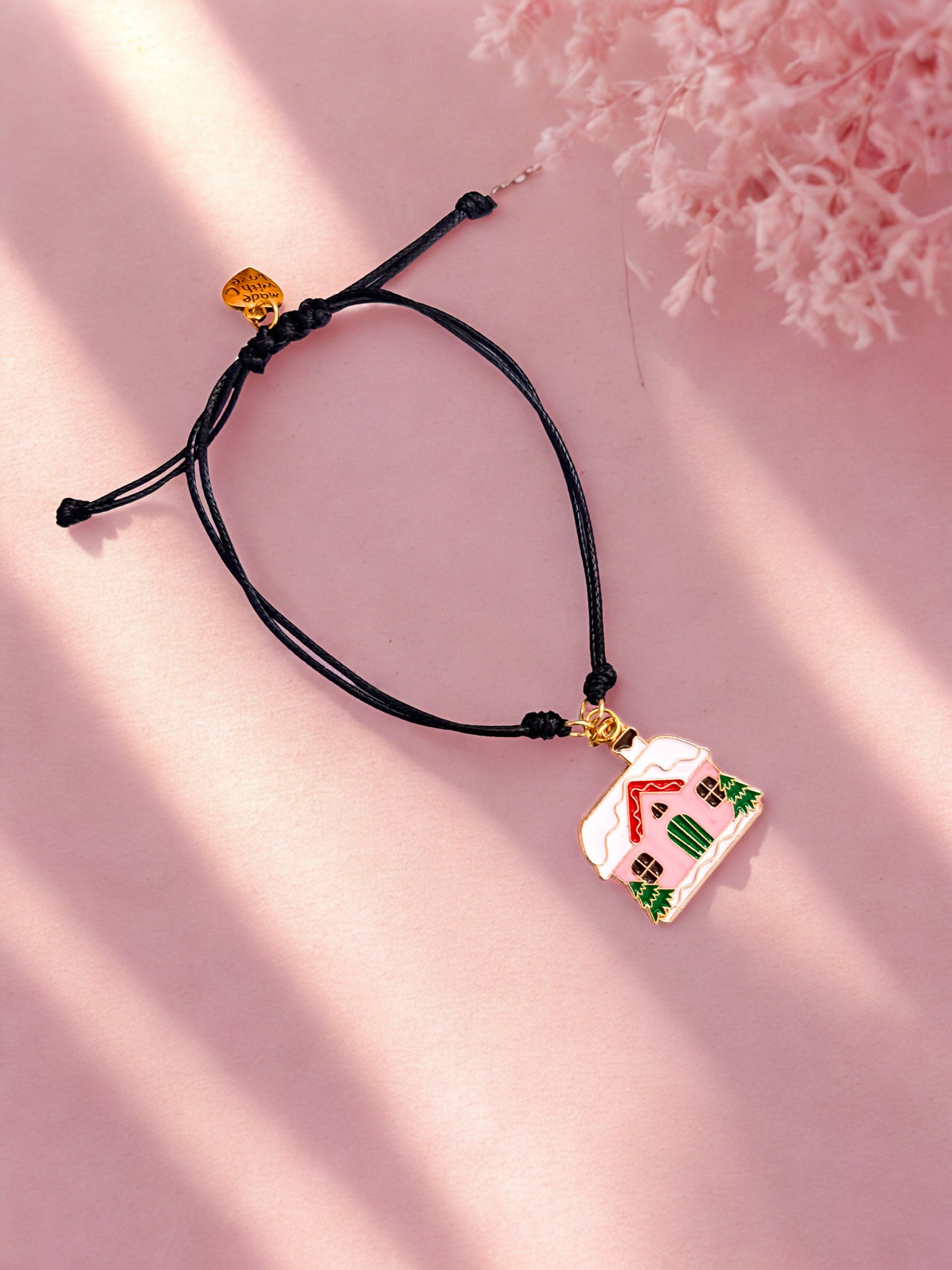 Bracelet with a house-shaped pendant on a pink background