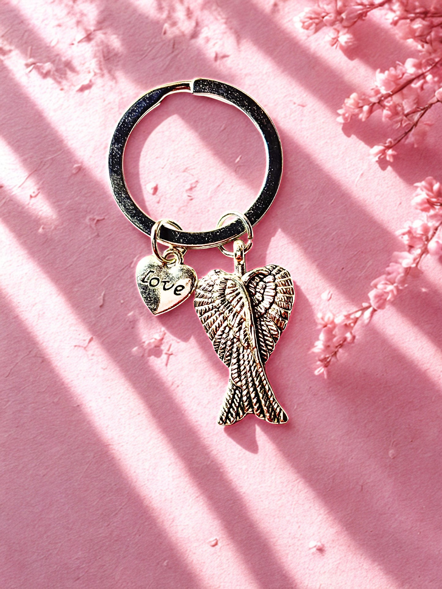 Keychain with angel wing and heart charm on a pink background