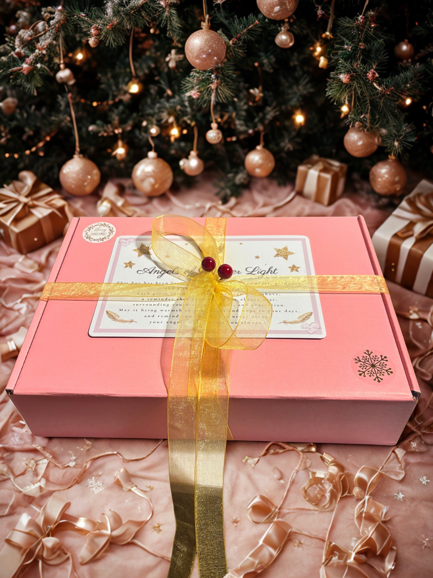 Pink gift box with gold ribbon under a decorated Christmas tree