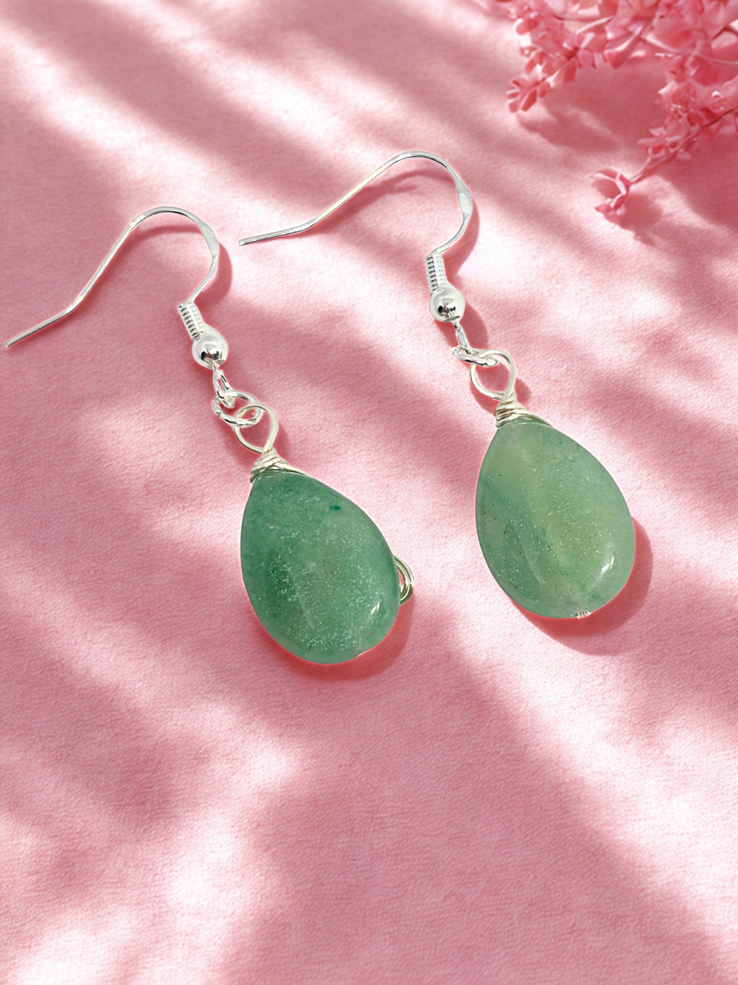 Green aventurine teardrop earrings on a pink background