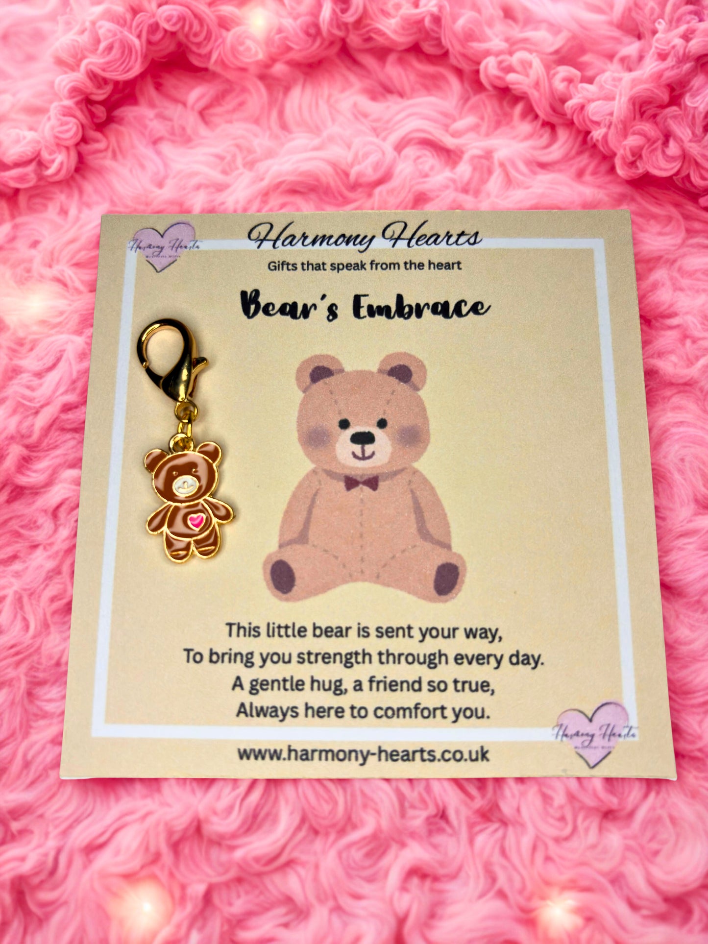 Bear-shaped keychain on a card with 'Harmony Hearts' branding against a pink textured background.