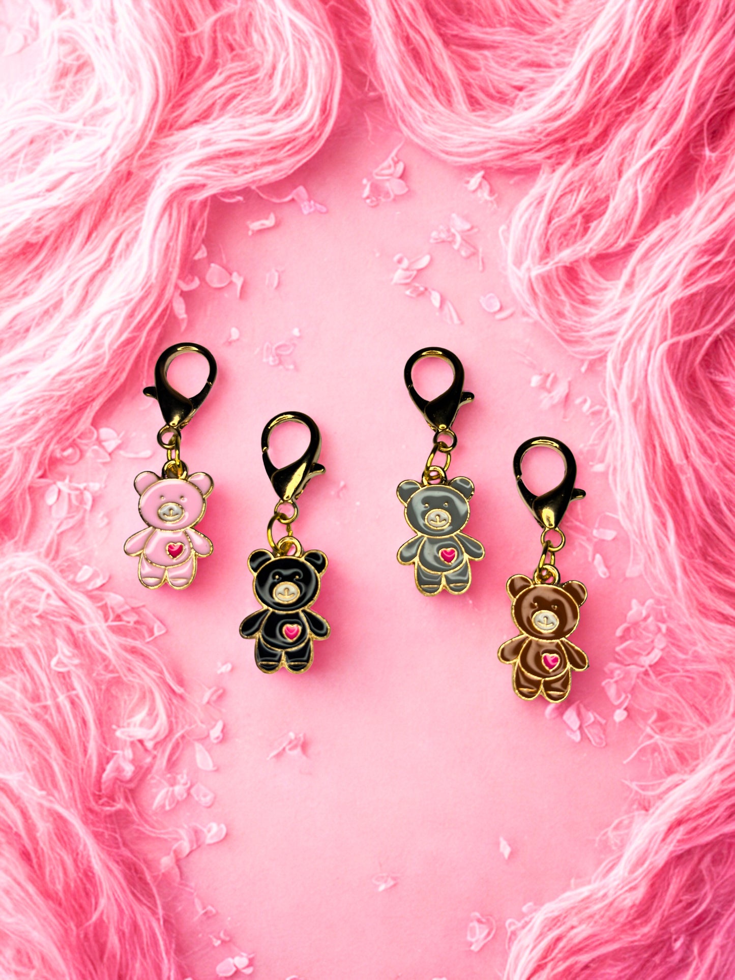 Four small bear-shaped keychains on a pink textured background