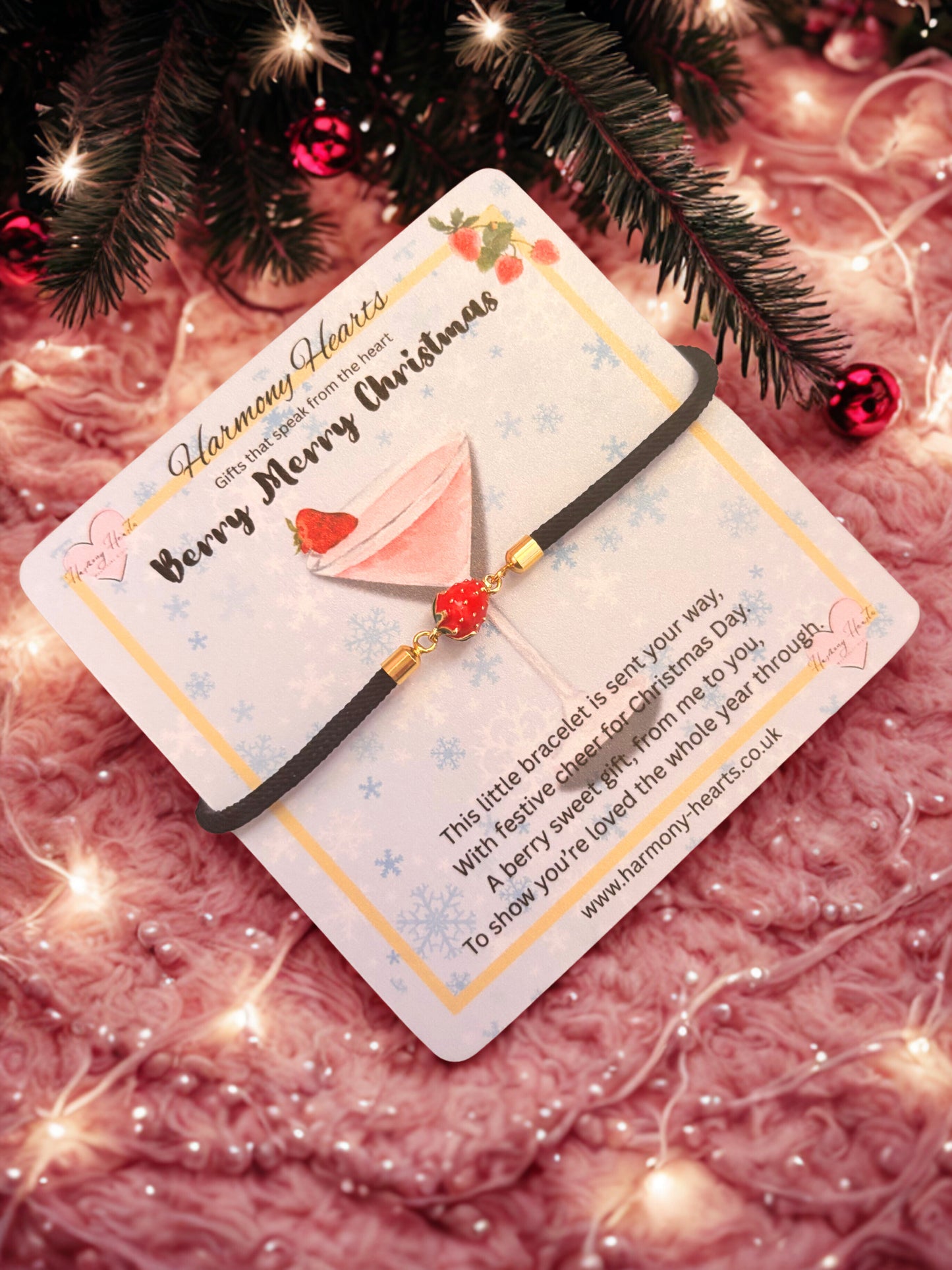 Bracelet with a strawberry charm on a card with Christmas decorations in the background