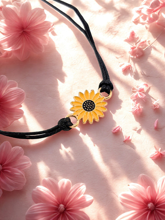 Yellow sunflower bracelet on a black cord against a pink floral background