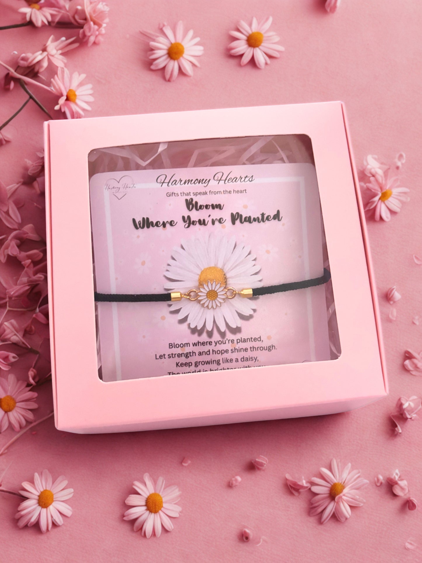 Pink gift box with 'Harmony Hearts' product on a pink background with daisies