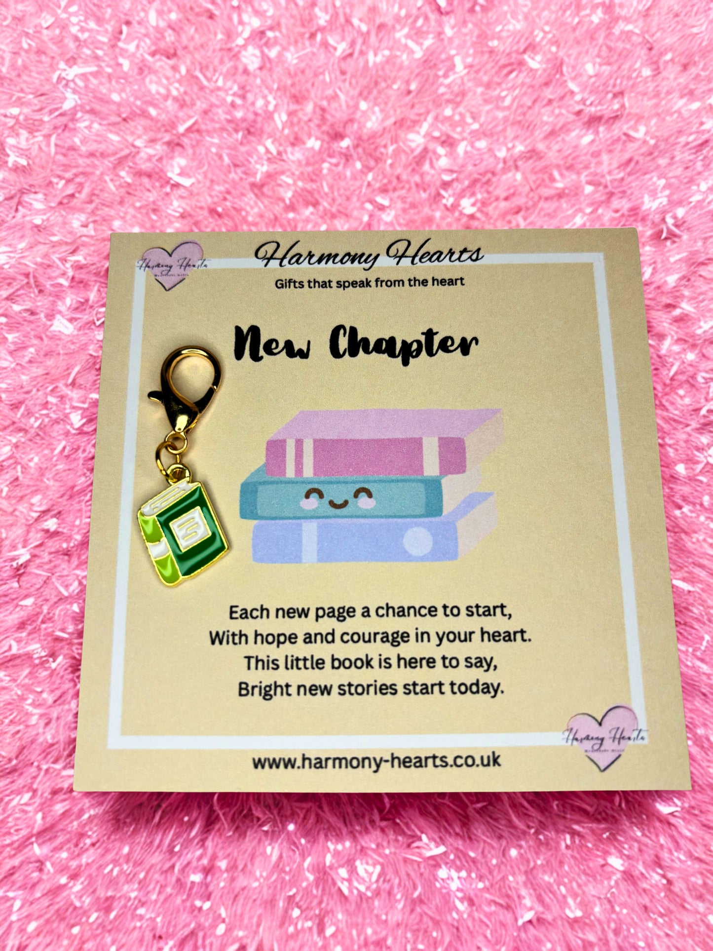 Book-shaped charm on a 'Harmony Hearts' card with text on a pink textured background