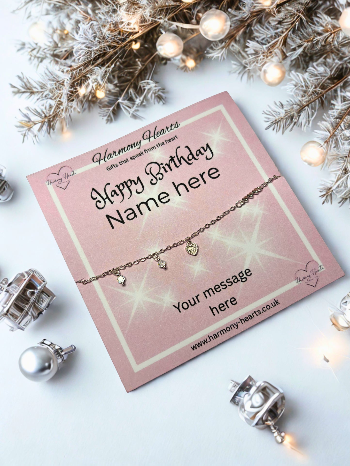 Bracelet on a pink card with 'Happy Birthday' message, surrounded by decorative lights and branches.