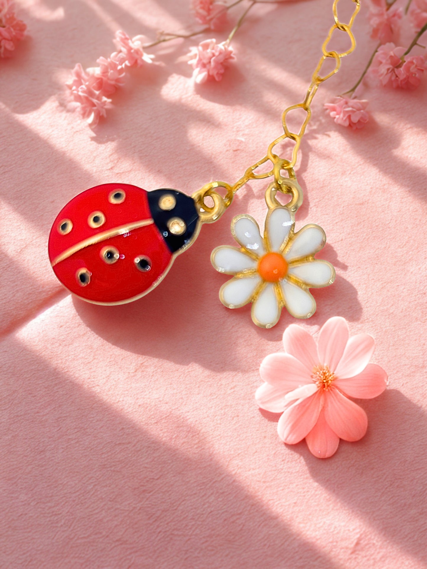 Charm with a ladybug and flower design on a pink background