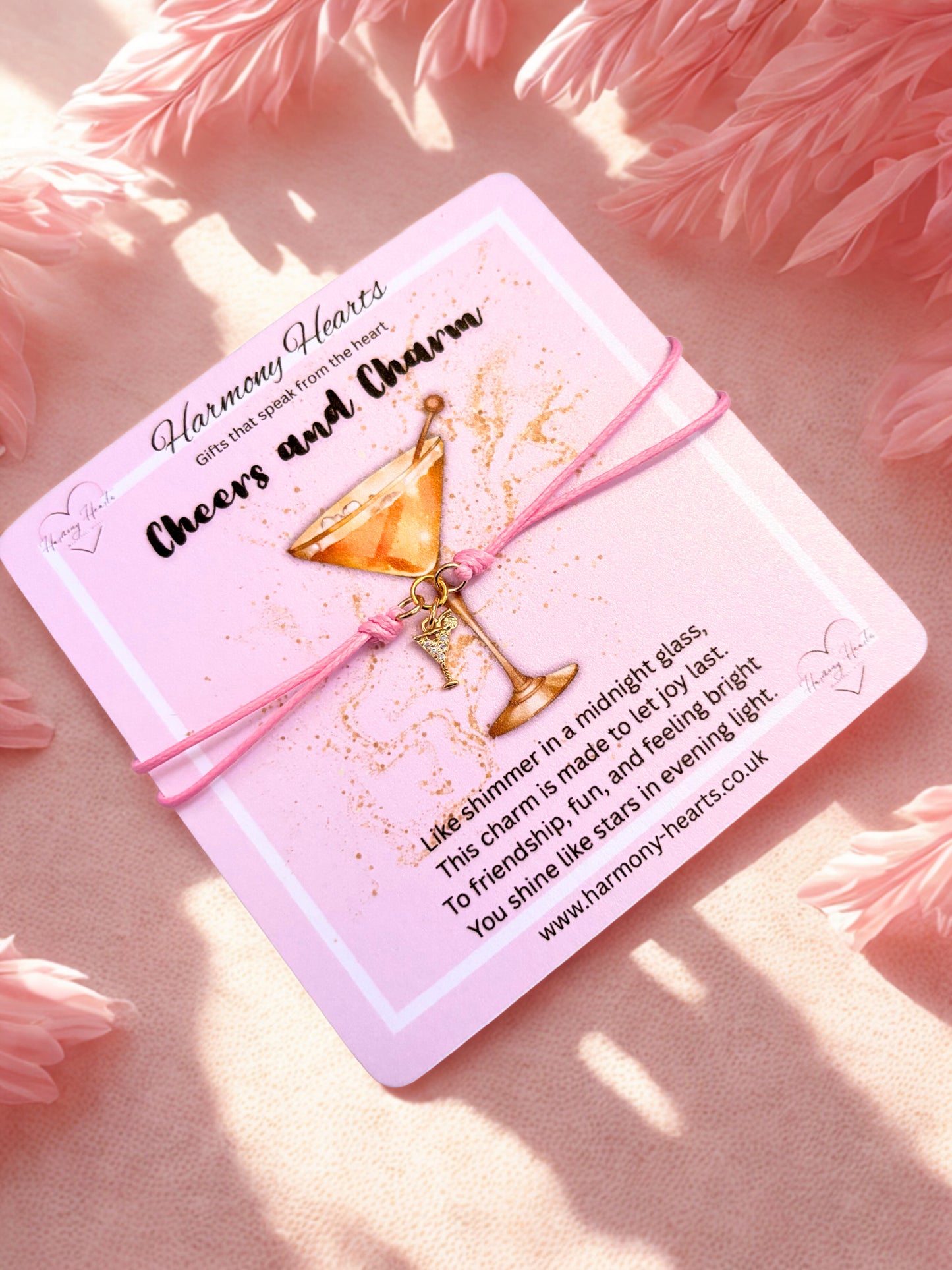 Pink bracelet with a cocktail charm on a poem card with a cocktail illustration and text on a pink fluffy background