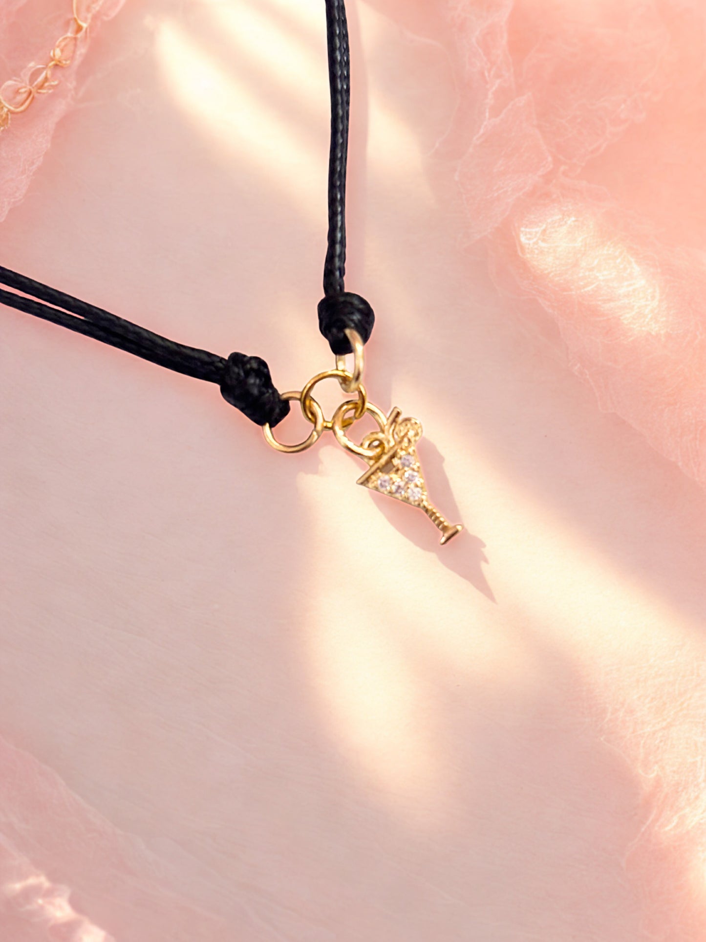 Bracelet with a gold cocktail charm on a pink fabric background