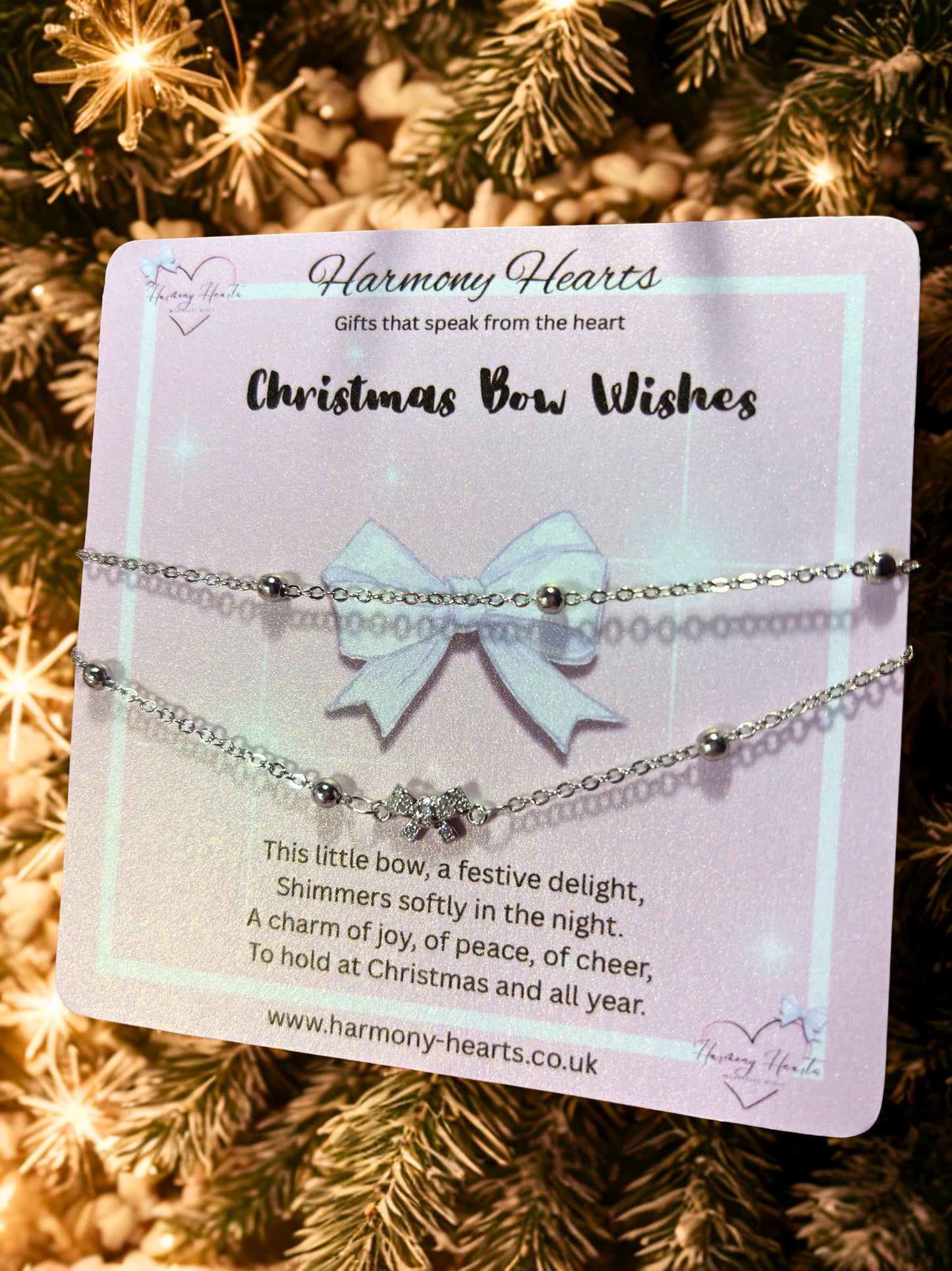 Jewelry set with a bow on a card labeled 'Harmony Hearts' against a Christmas tree background.