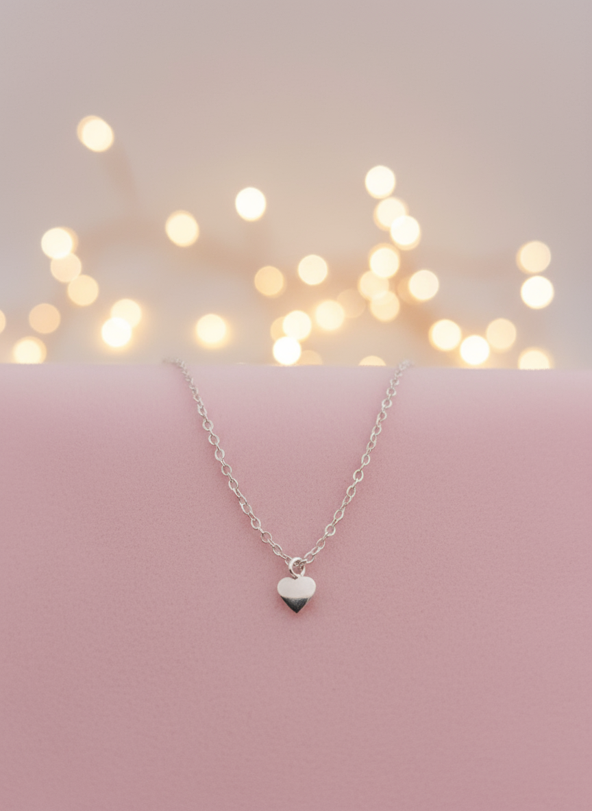Silver heart-shaped bracelet on a pink surface with blurred lights in the background