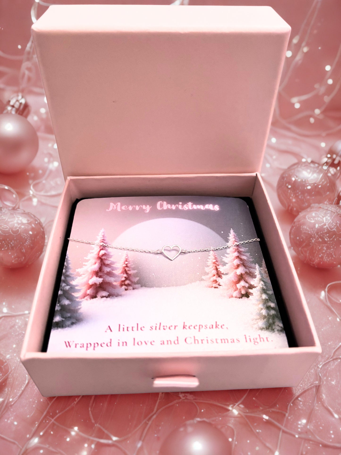 Pink jewelry box with Christmas-themed design and silver heart bracelet