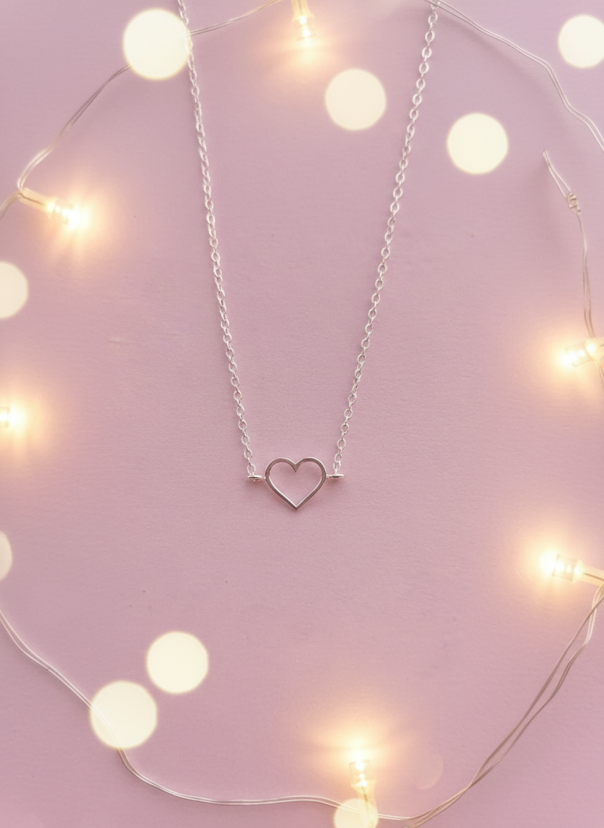Silver heart-shaped bracelet on a pink background with string lights