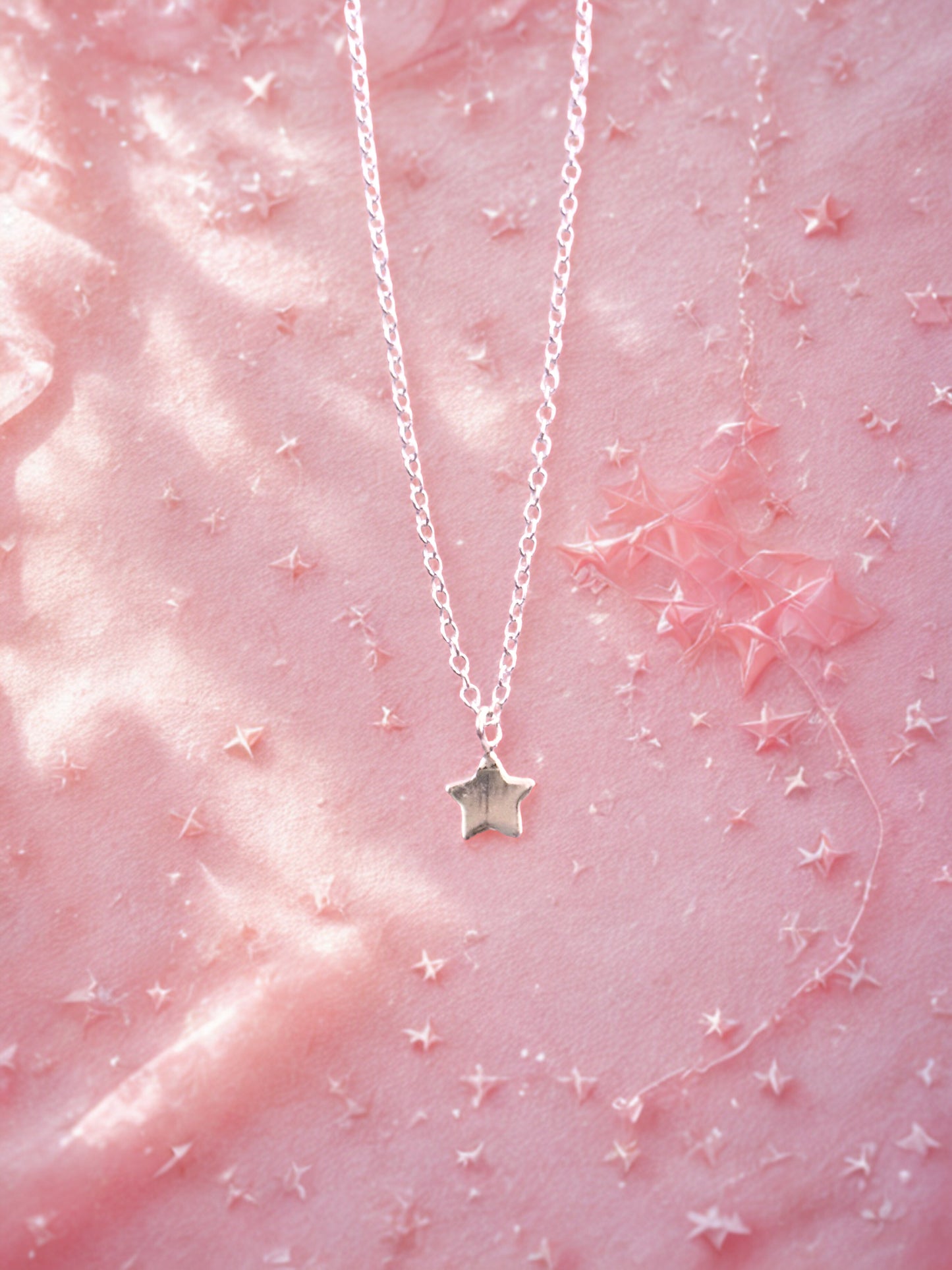 Silver star bracelet on a pink textured background with star decorations