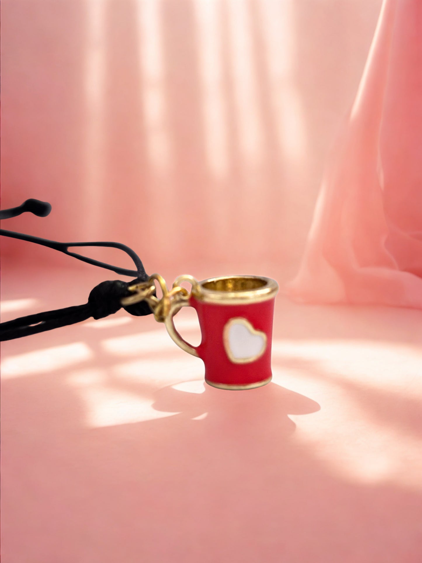 Red cup charm with gold rim on a pink fabric background