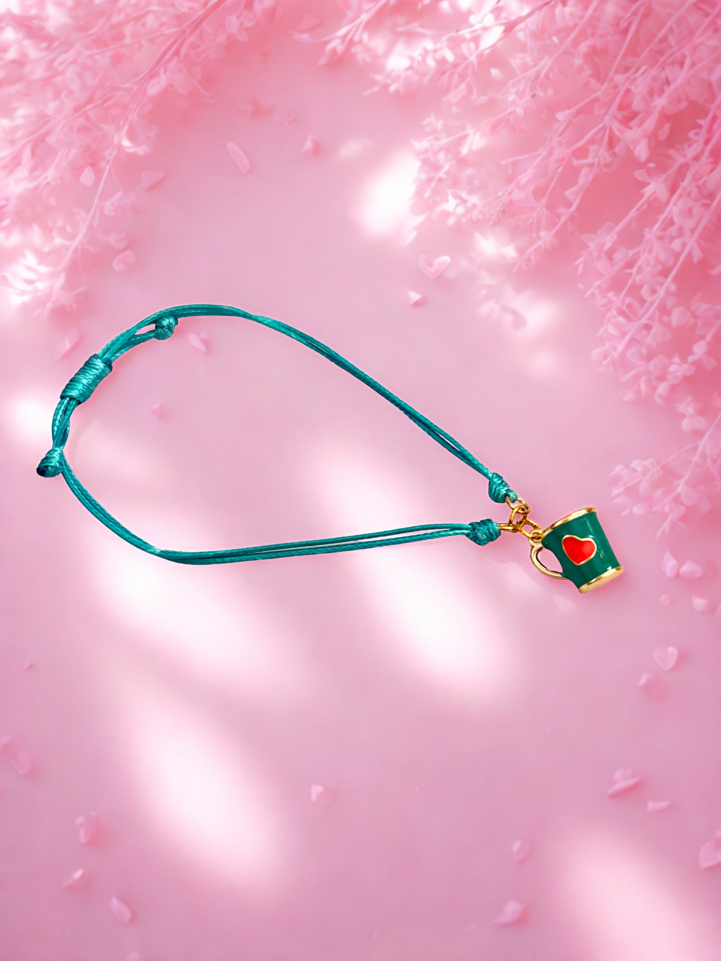Teal mug charm bracelet with a red heart on a pink background