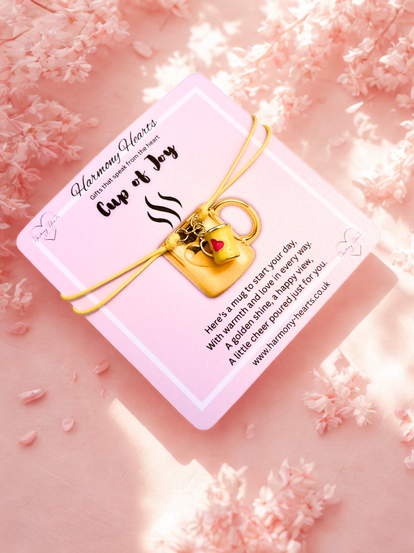 Bracelet with a mug charm on a pink card against a pink floral background