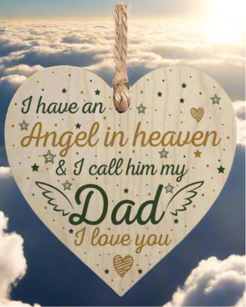 Heart-shaped wooden plaque with text about an angel in heaven, hanging against a cloudy sky.