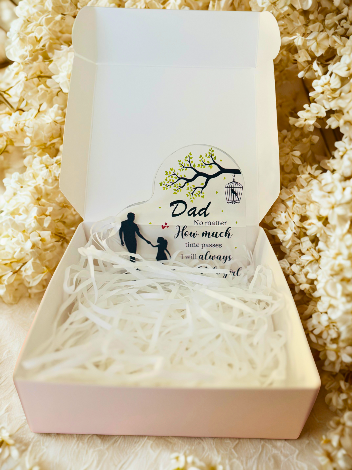 Gift box with an acrylic plaque inside, surrounded by decorative paper on a textured surface