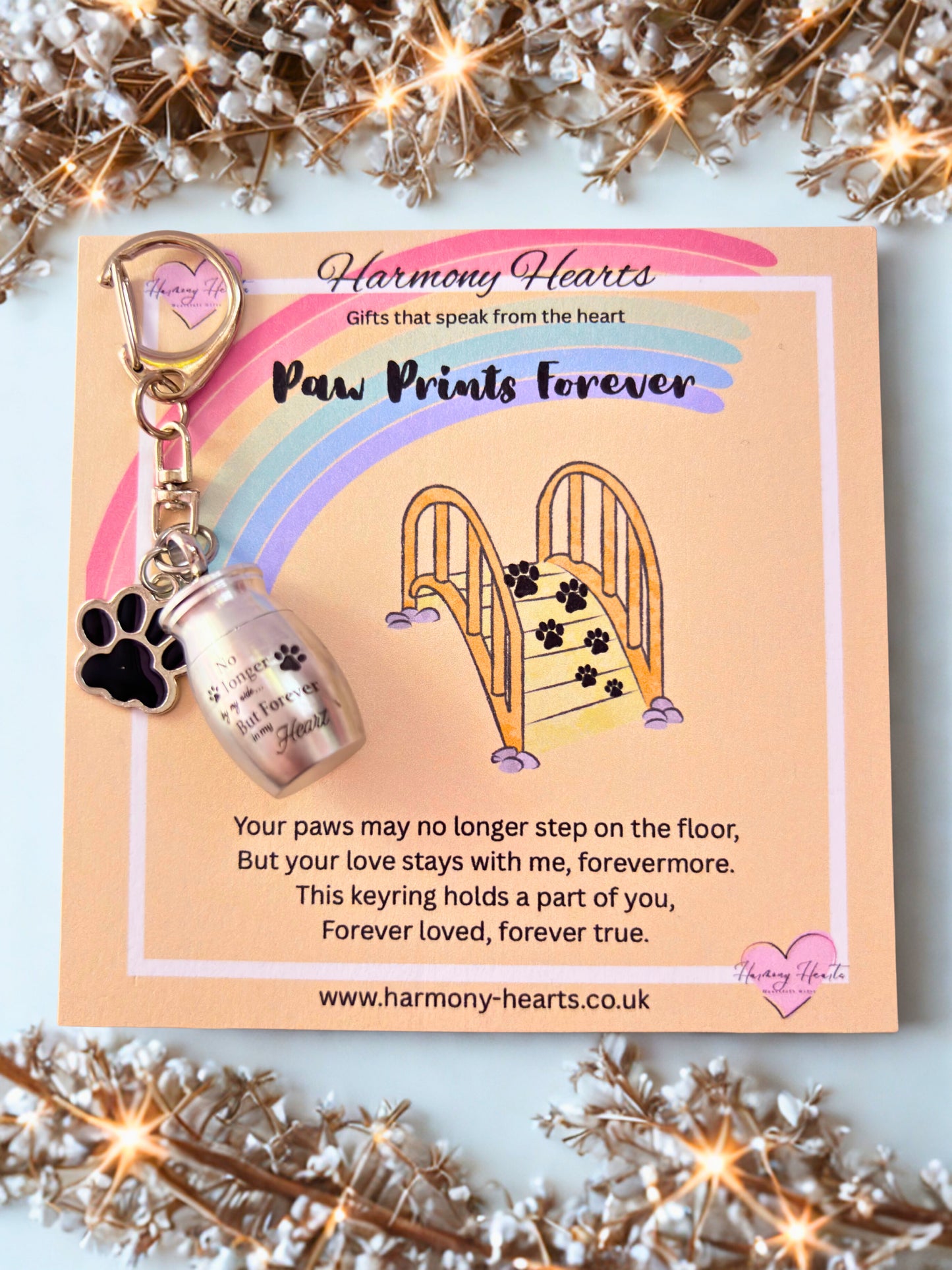 Keychain with bottle and paw print design on a 'Harmony Hearts' card with decorative elements.