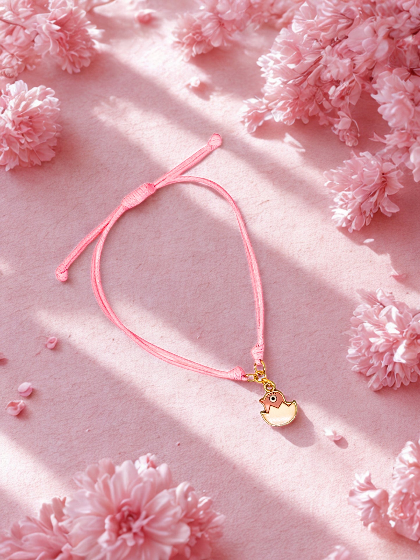 Pink bracelet with an Easter Chick charm on a pink floral background