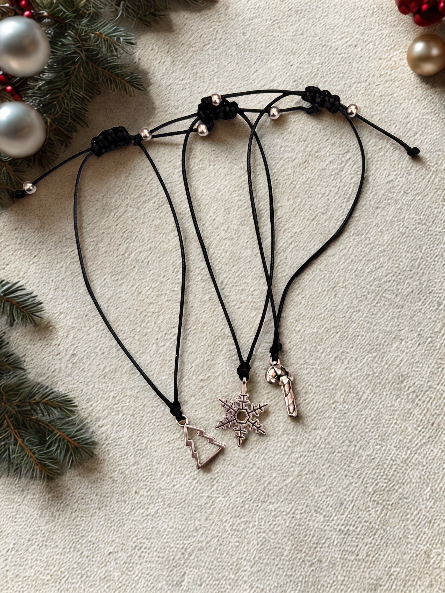 Silver-tone charms on black cord bracelets with Christmas tree, snowflake and candy cane