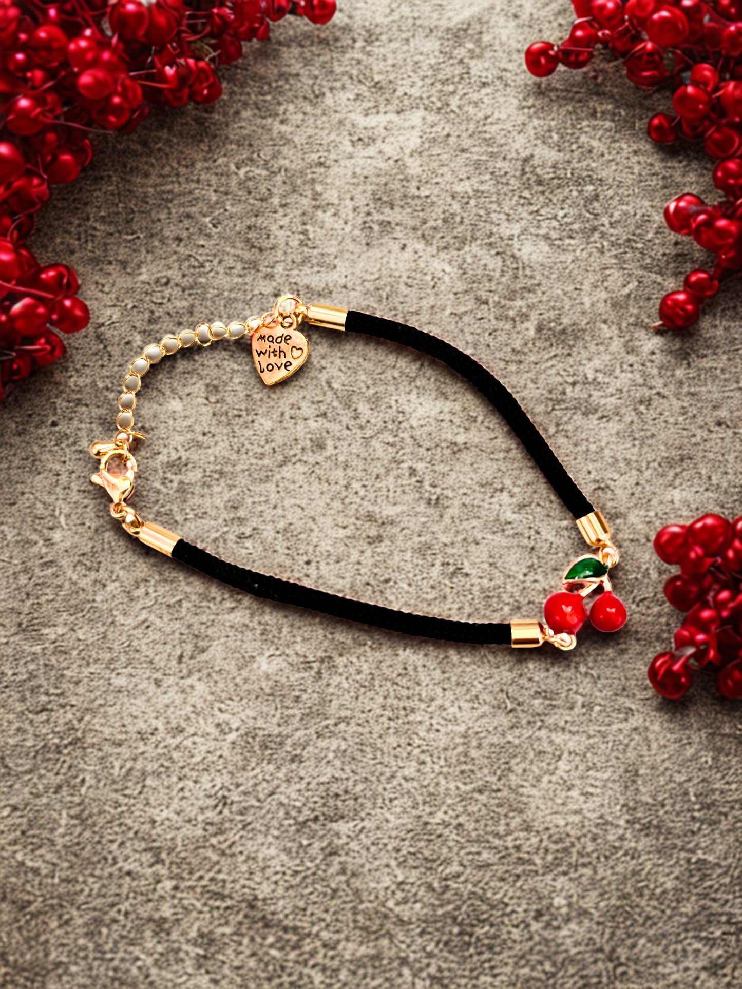 Bracelet with cherry charm and on a festive surface with red berries