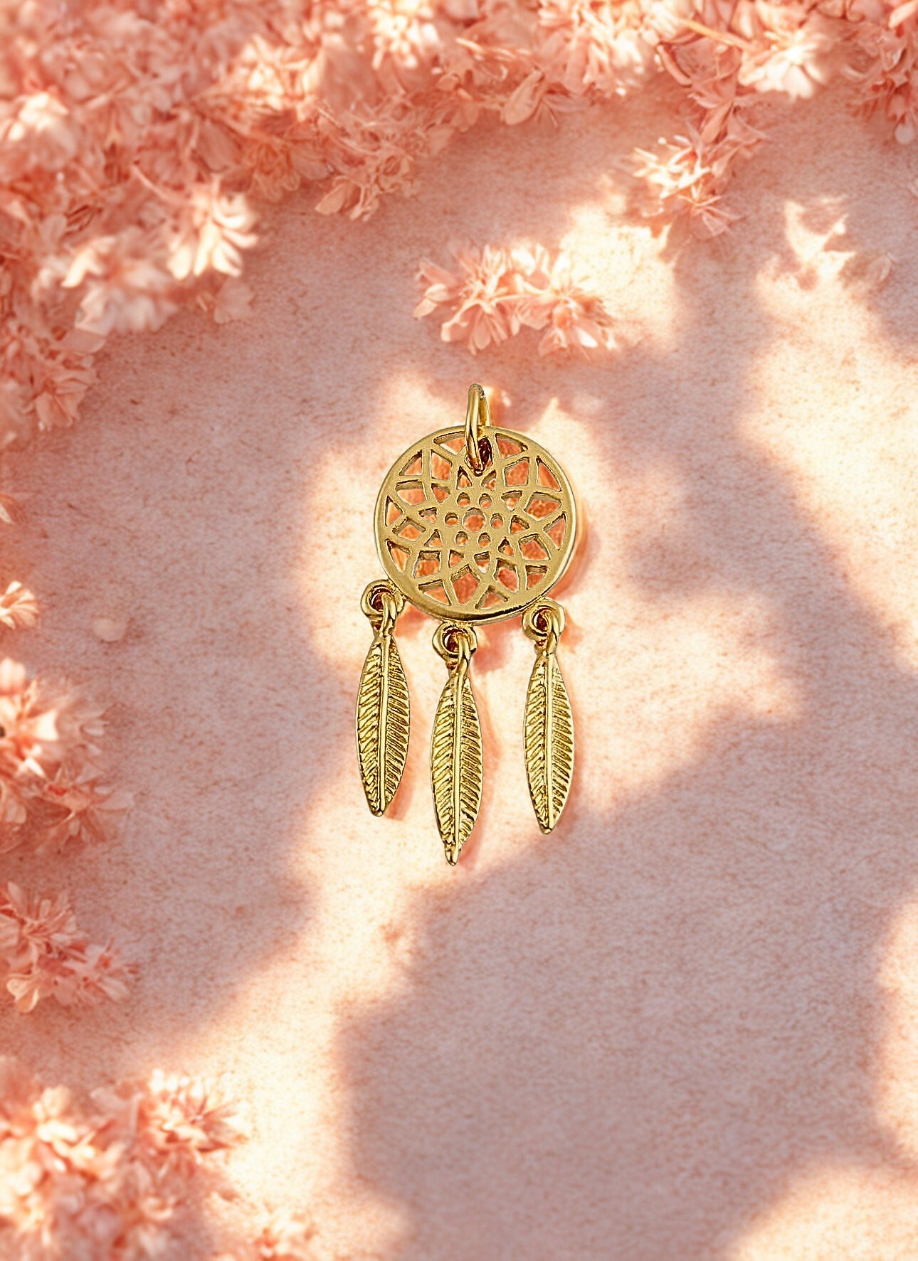 Gold dreamcatcher charm on a pink floral background