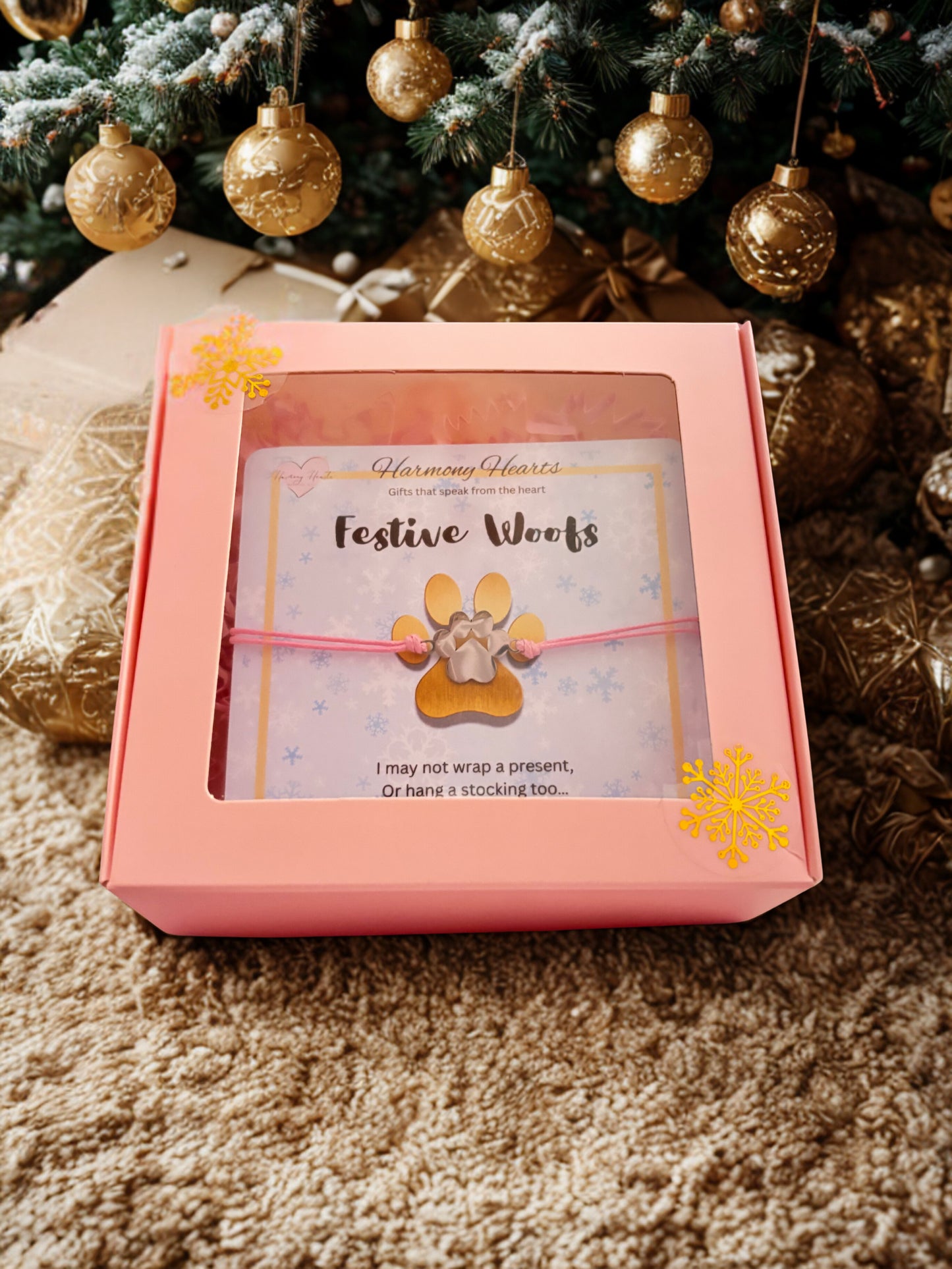 Pink gift box with 'Festive Woofs' card and dog collar against a Christmas tree background