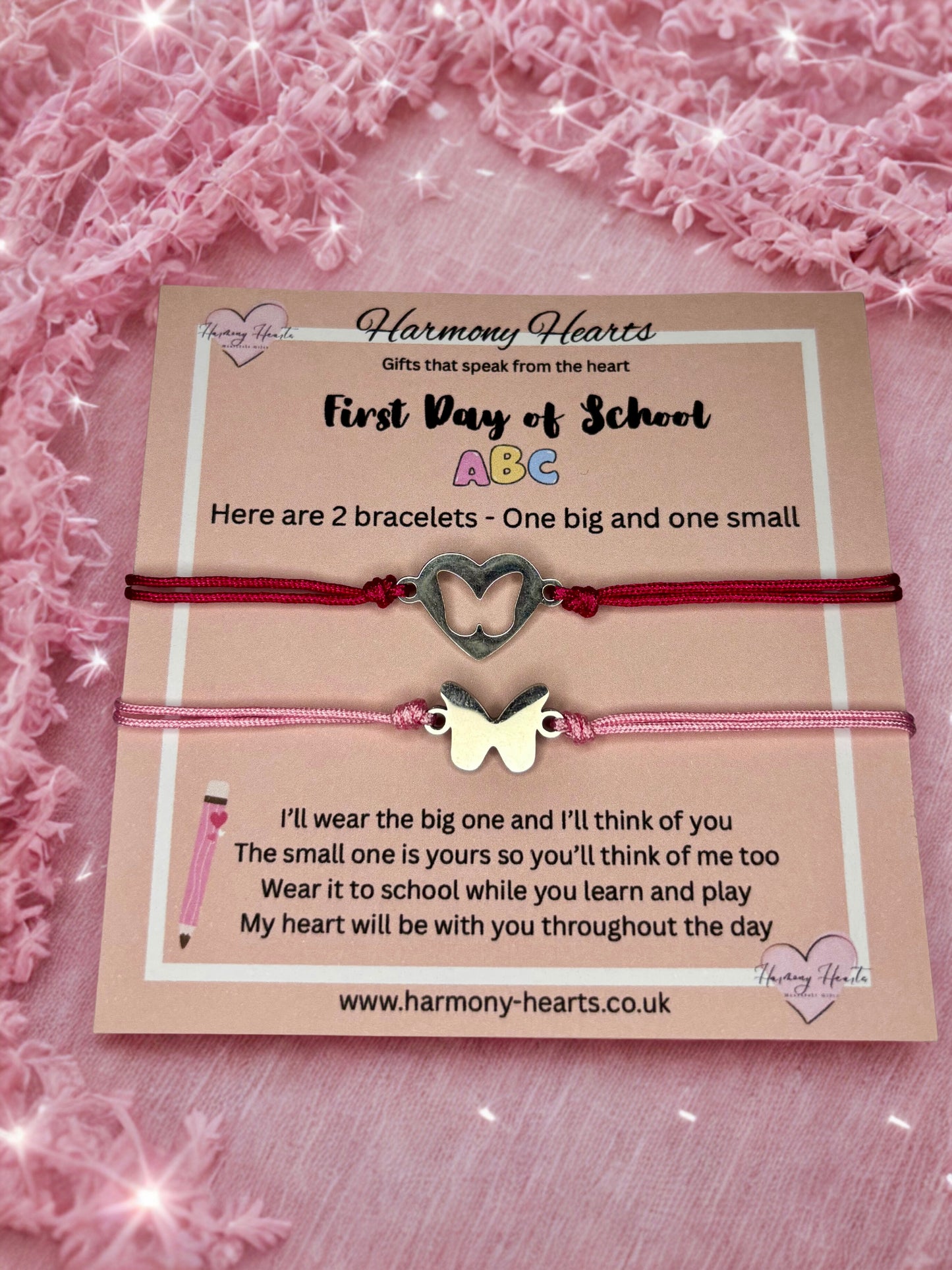 Two bracelets with heart and butterfly charms on a card with text, against a pink textured background.
