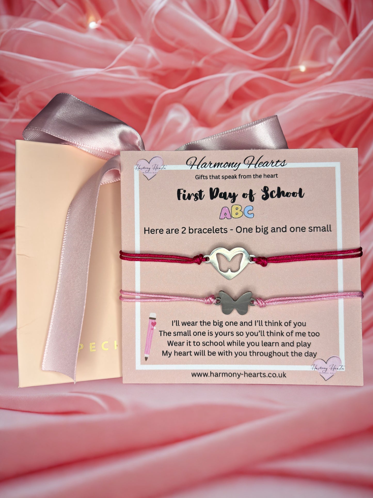 Bracelets with butterfly charms on a card with text, against a pink fabric background