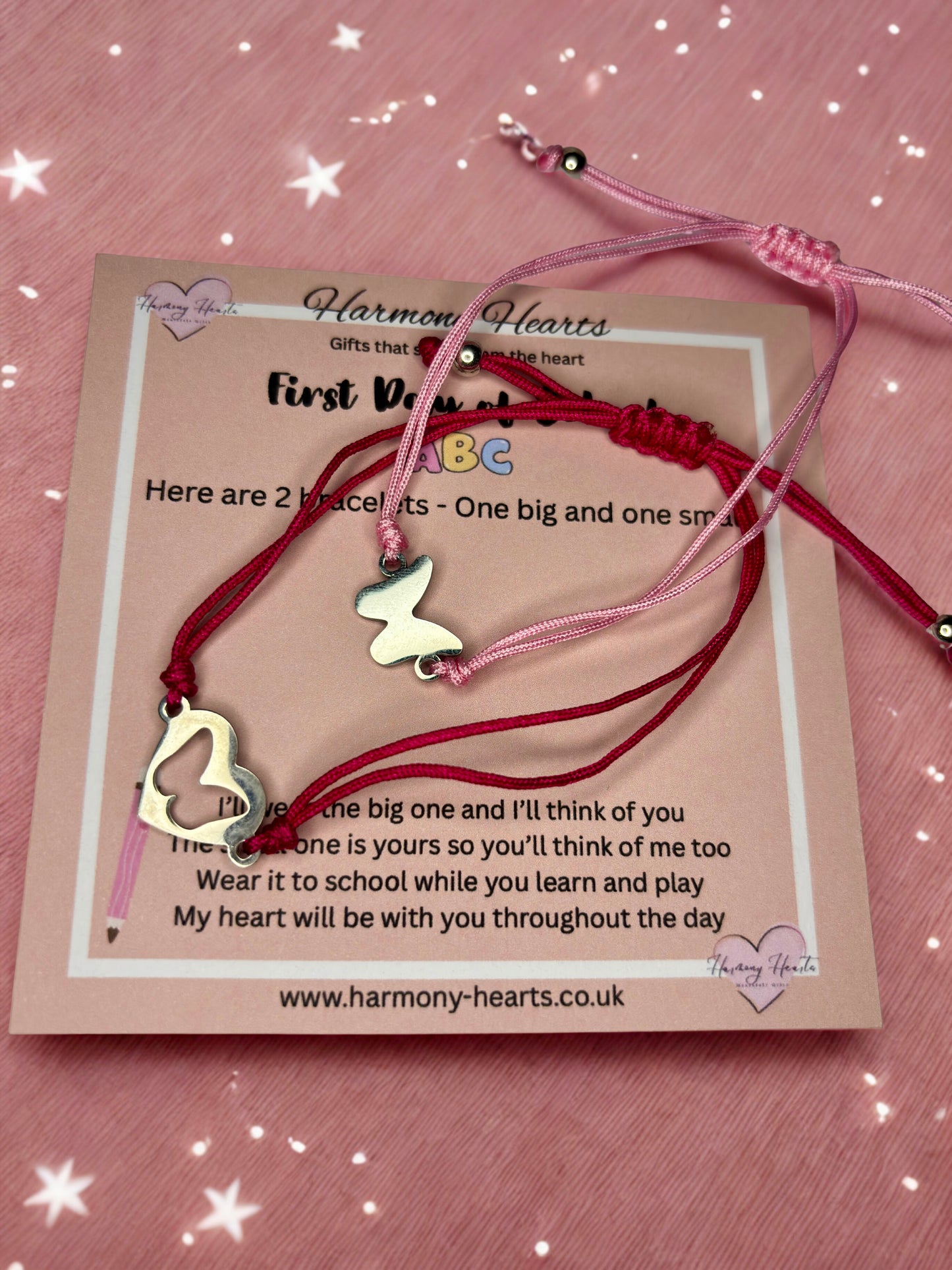 Two bracelets with heart and butterfly charms on a card with text, against a pink background.
