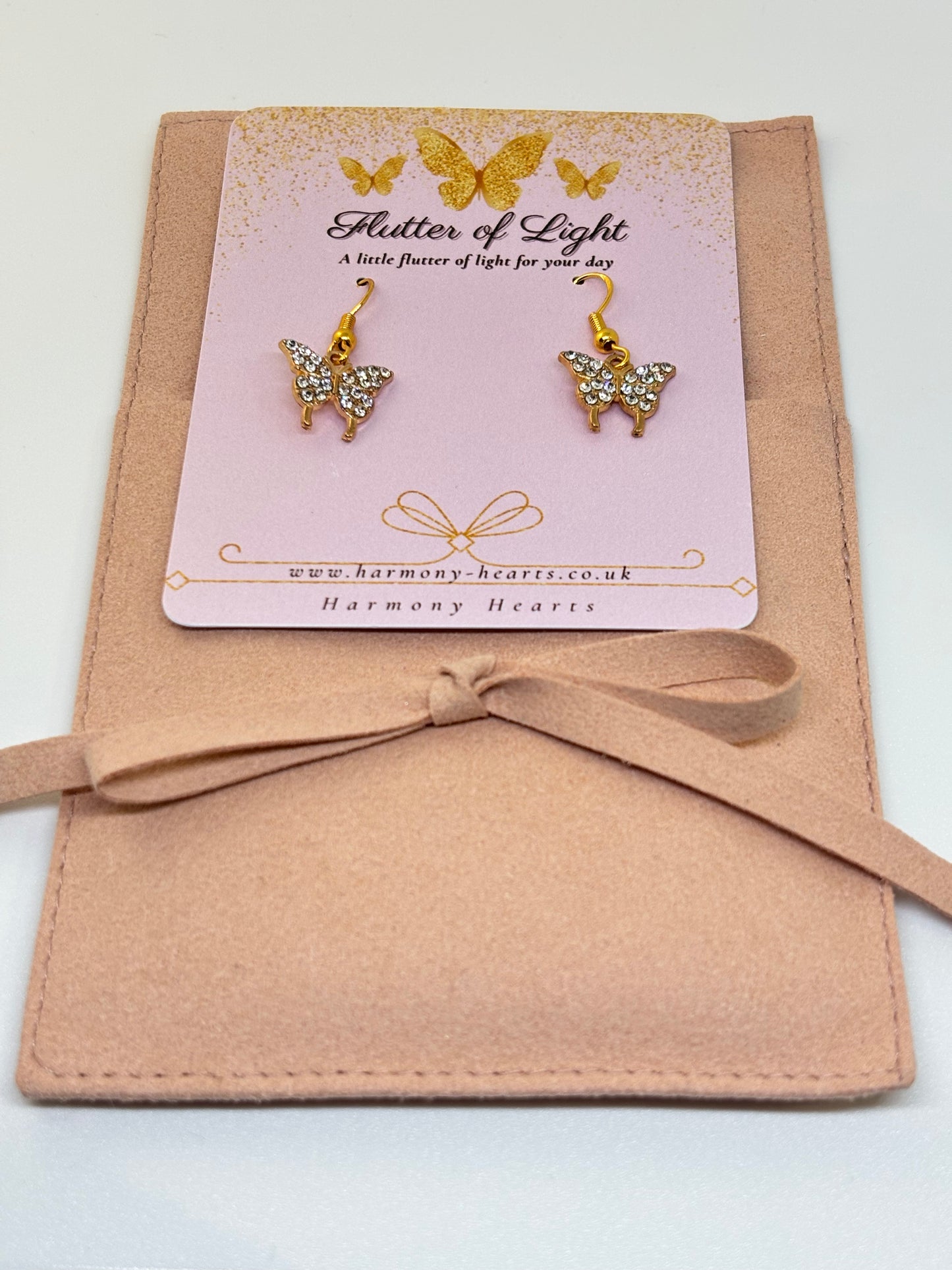 Butterfly earrings on a 'Flutter of Light' card with a pink bow on a white background