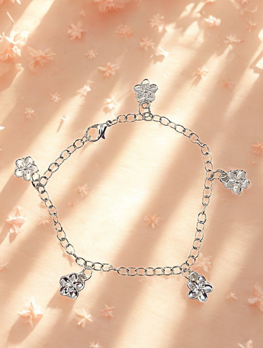 Silver charm bracelet with flowers charms on a blush background