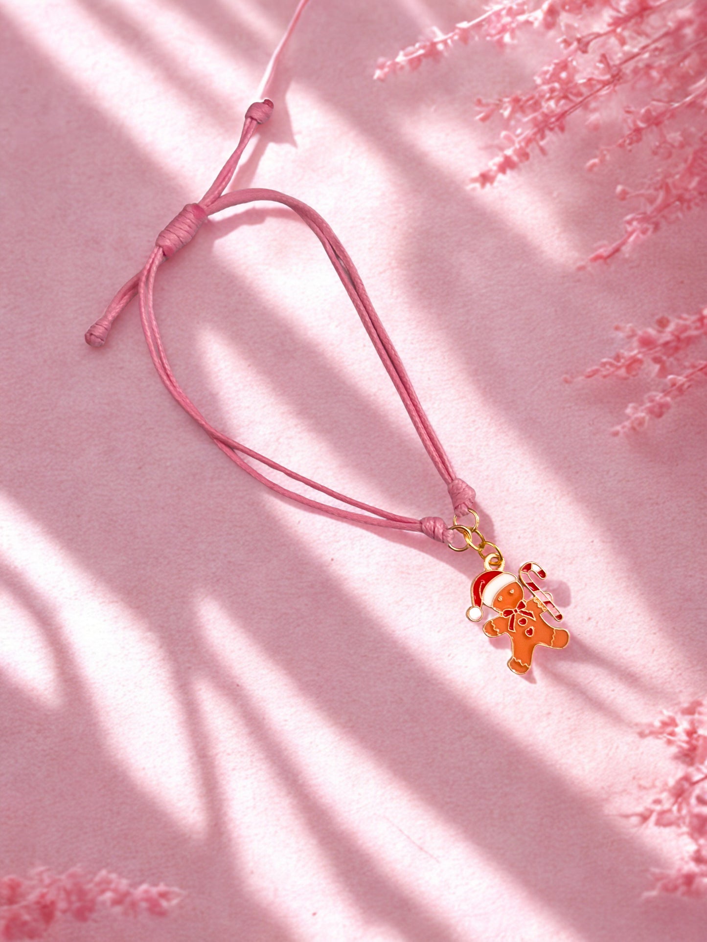 Pink cord with a gingerbread man charm on a pink background
