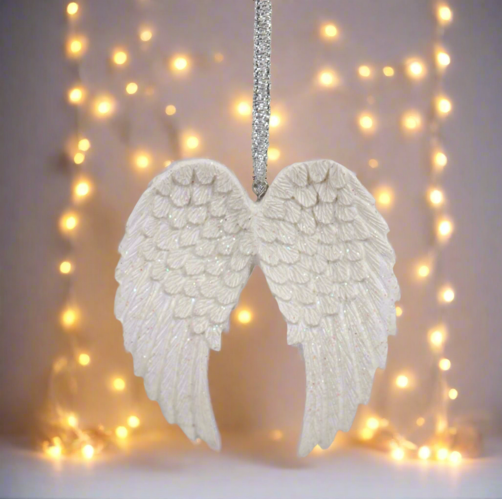 Decorative angel wings hanging against a soft glow of string lights.
