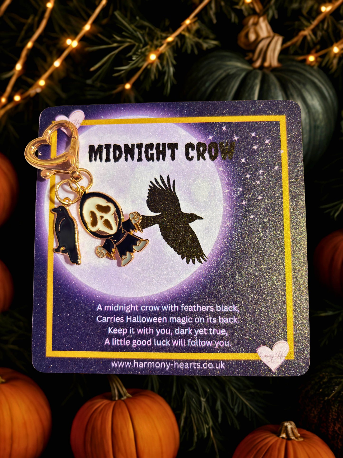 Midnight Crow keychain on a card with pumpkins and string lights in the background