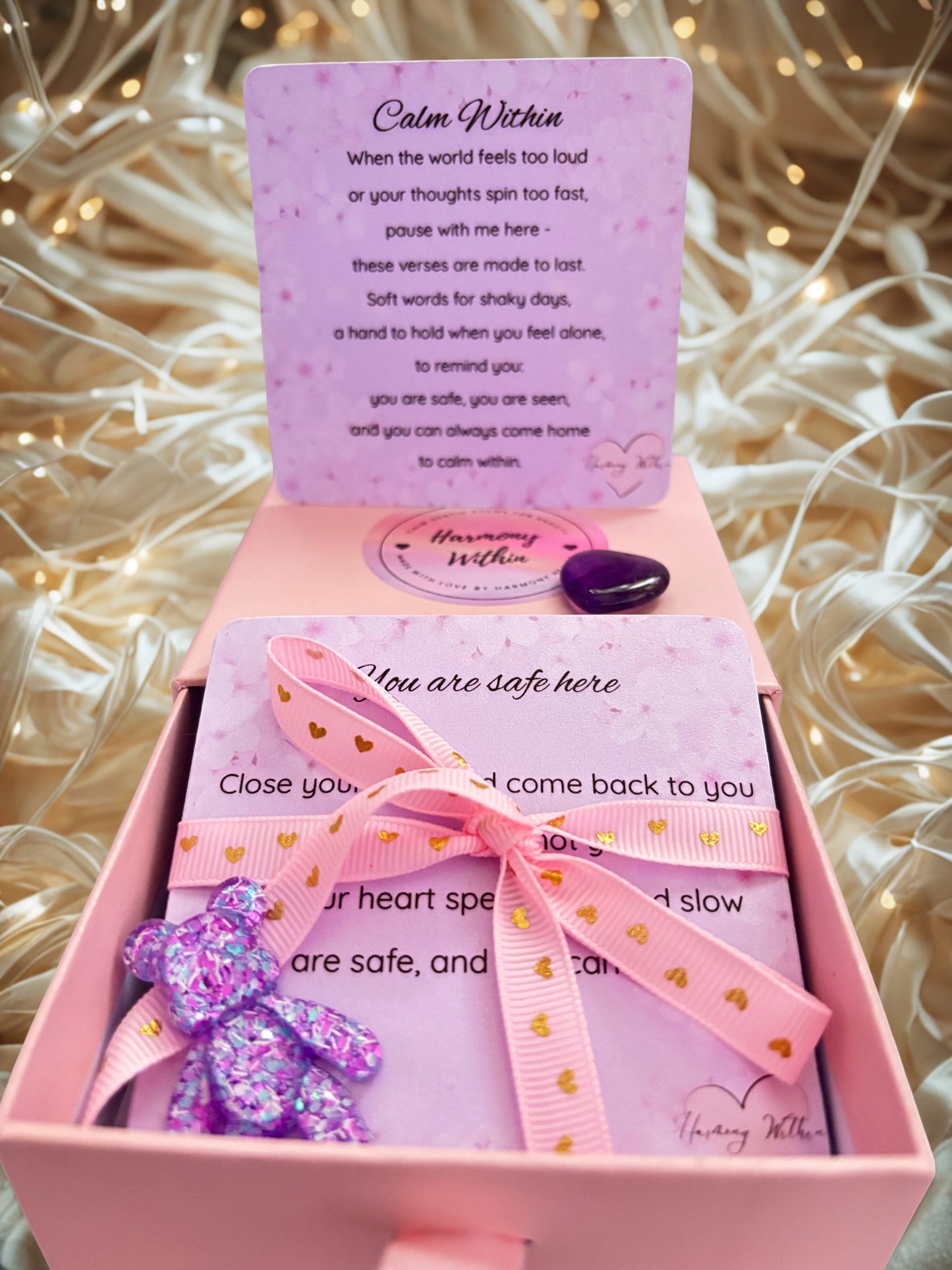 Pink gift box with a purple card and decorative elements on a textured background