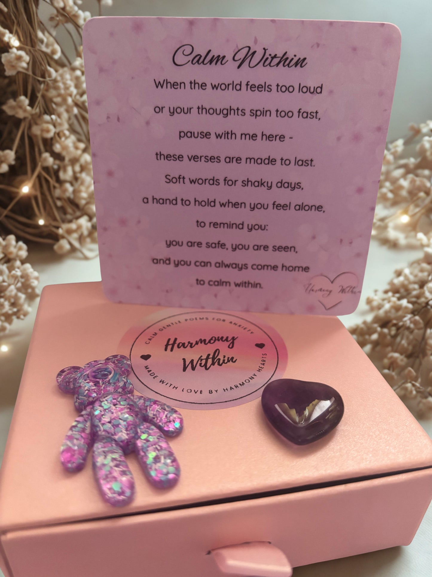 Pink box with a heart-shaped object and a purple card with text on a light background