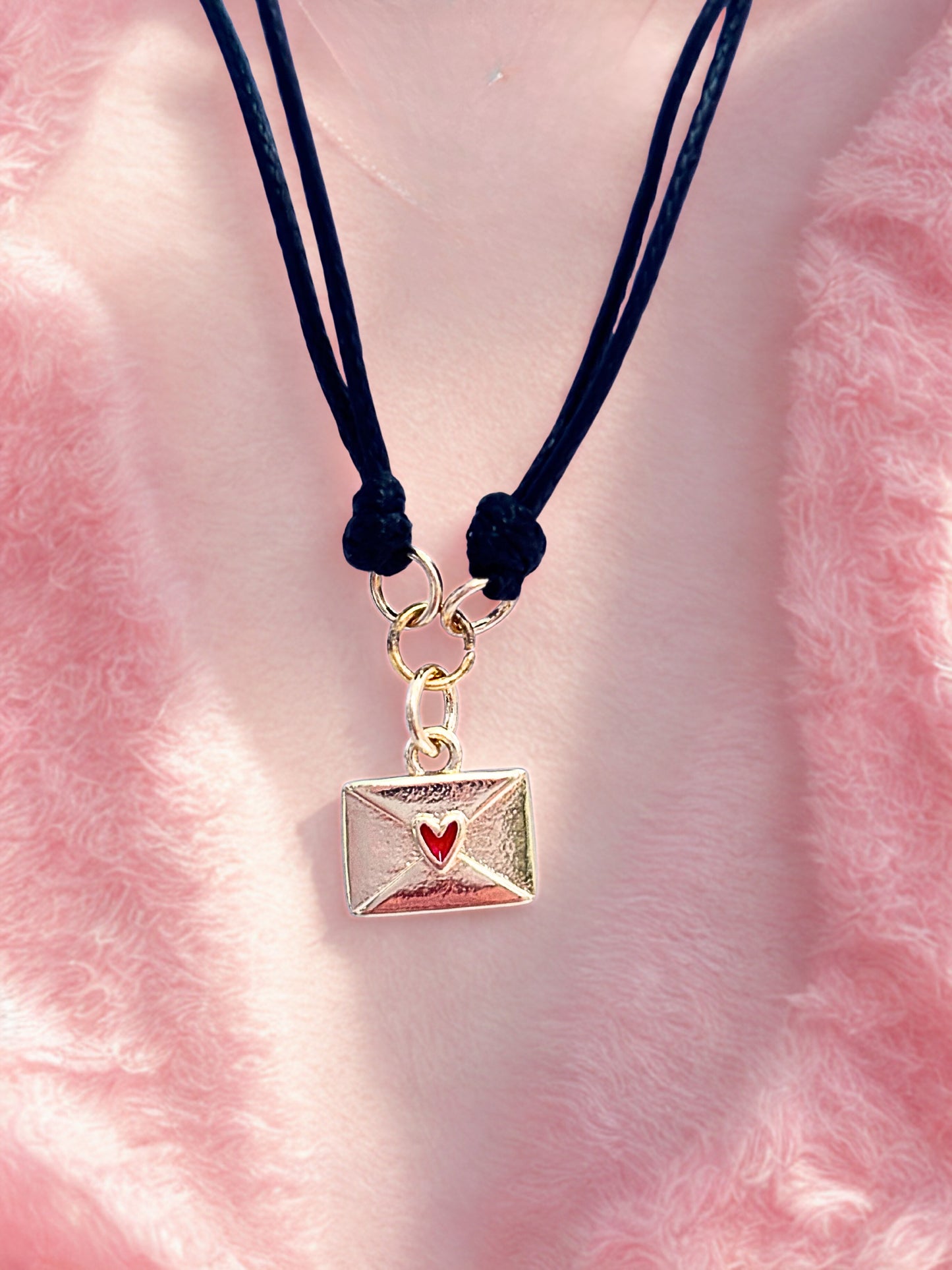 Bracelet with a gold envelope charm on a pink fluffy background