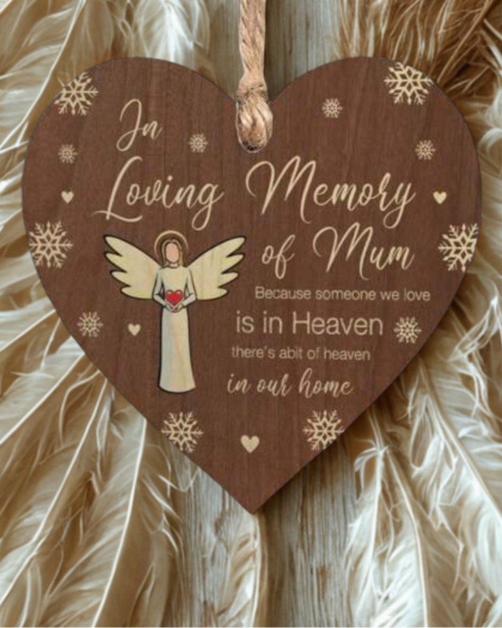 Heart-shaped wooden plaque with an angel illustration and text about loving memory of Mum on a textured background.