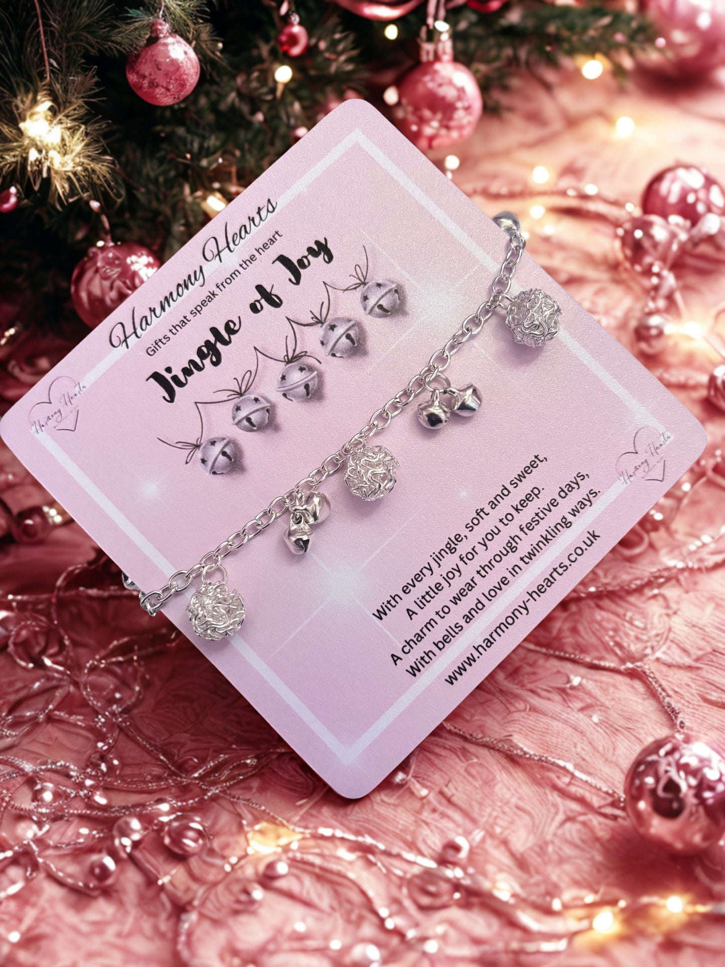 Silver tone bracelet with charms on a pink card against a festive background