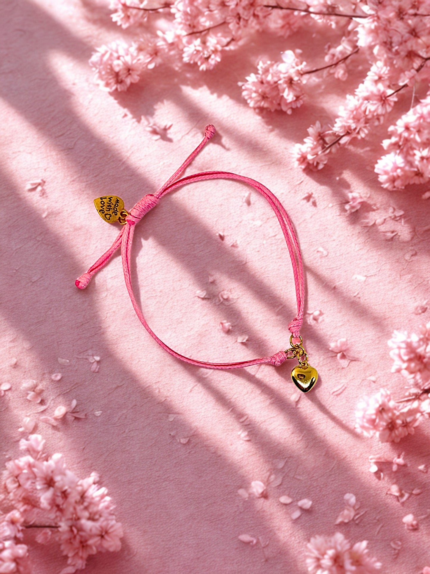 Pink bracelet with heart charms on a pink floral background