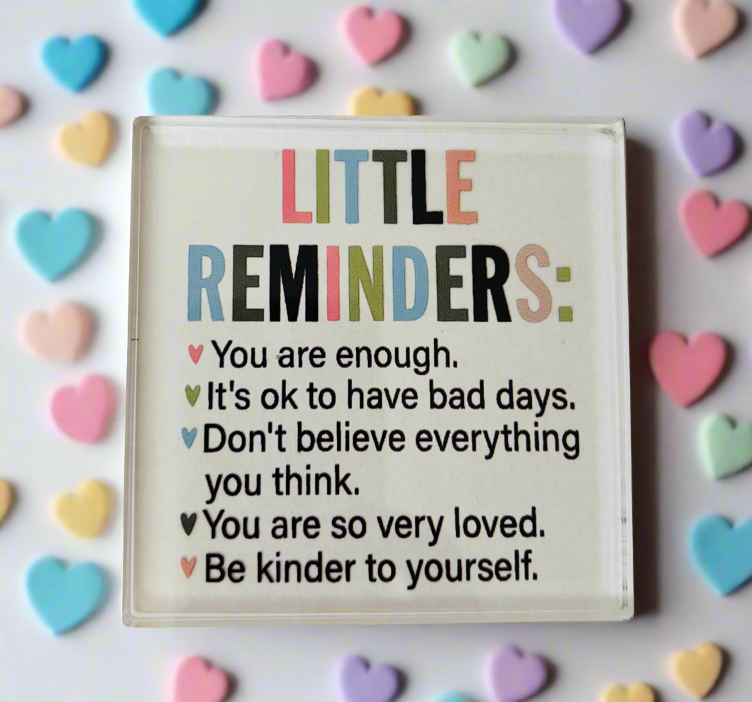Motivational sign with inspirational quotes surrounded by colorful heart-shaped candies on a light background