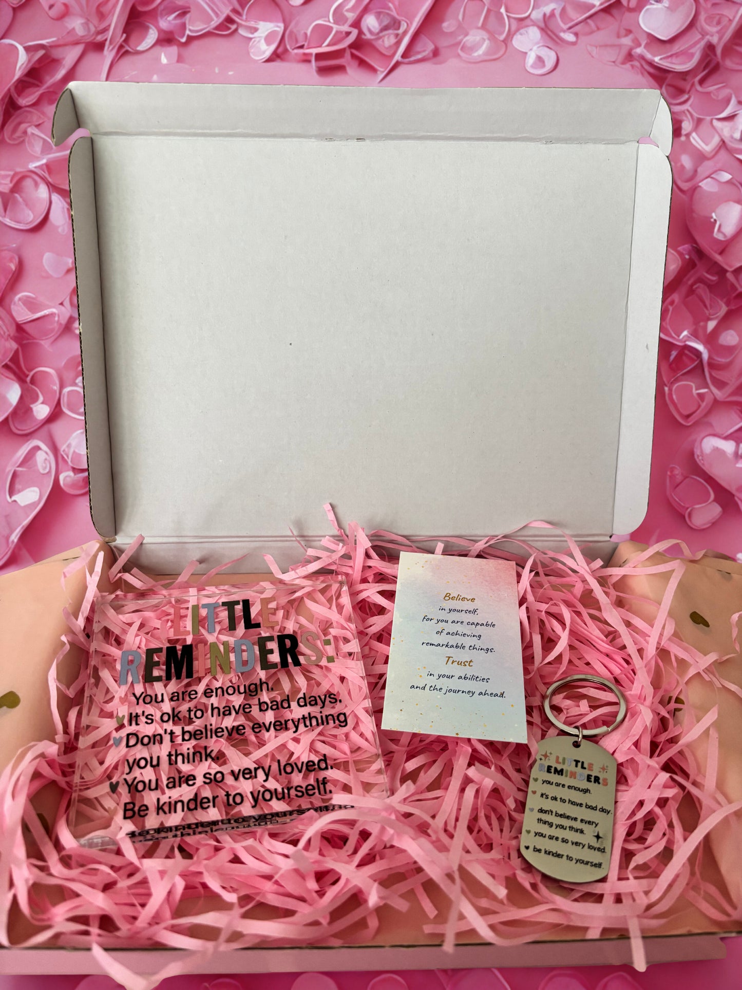 Gift box with pink interior, pink heart-shaped confetti, and a keychain with a message card.