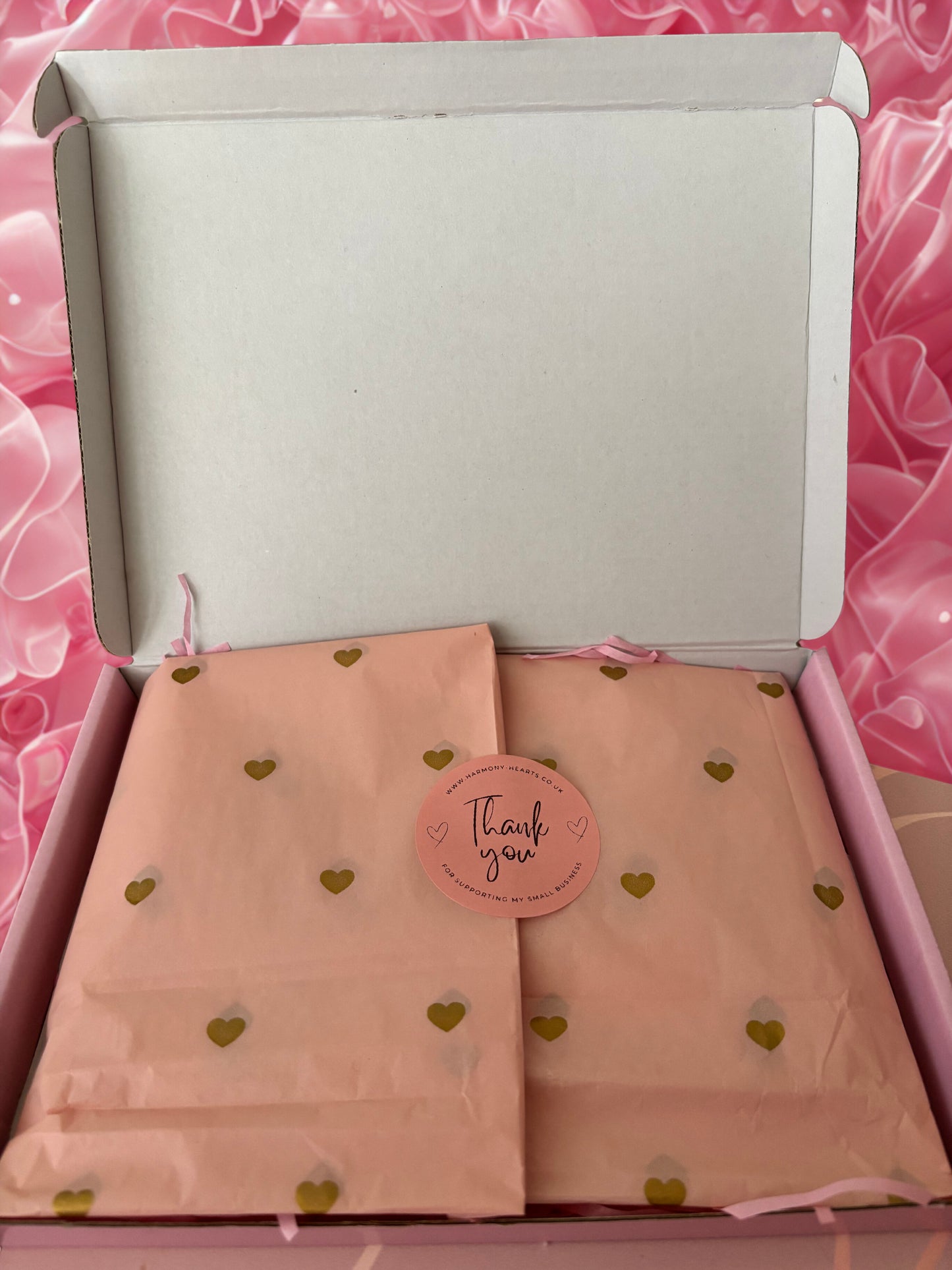 Pink fabric with gold heart patterns in a box on a pink floral background