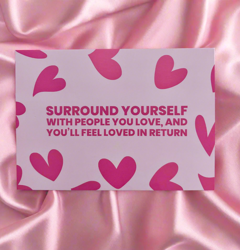 Motivational card with heart design and text on a pink satin background